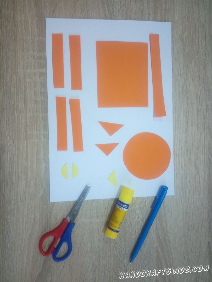 Для начала берем в руки бумагу оранжевого цвета и ножницы. Вырезаем все необходимые детальки: широкий прямоугольник, круг, 2 маленьких треугольника, 2 короткие полоски одинакового размера и одна полоска чуть длиннее. Затем берем желтую бумагу и вырезаем маленький треугольник и кружок, который разрежем пополам. Переходим к шагу №2