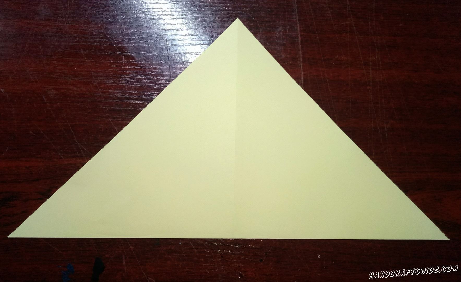Светло-желтый квадратный лист бумаги мы складываем пополам, в такой вот треугольник.