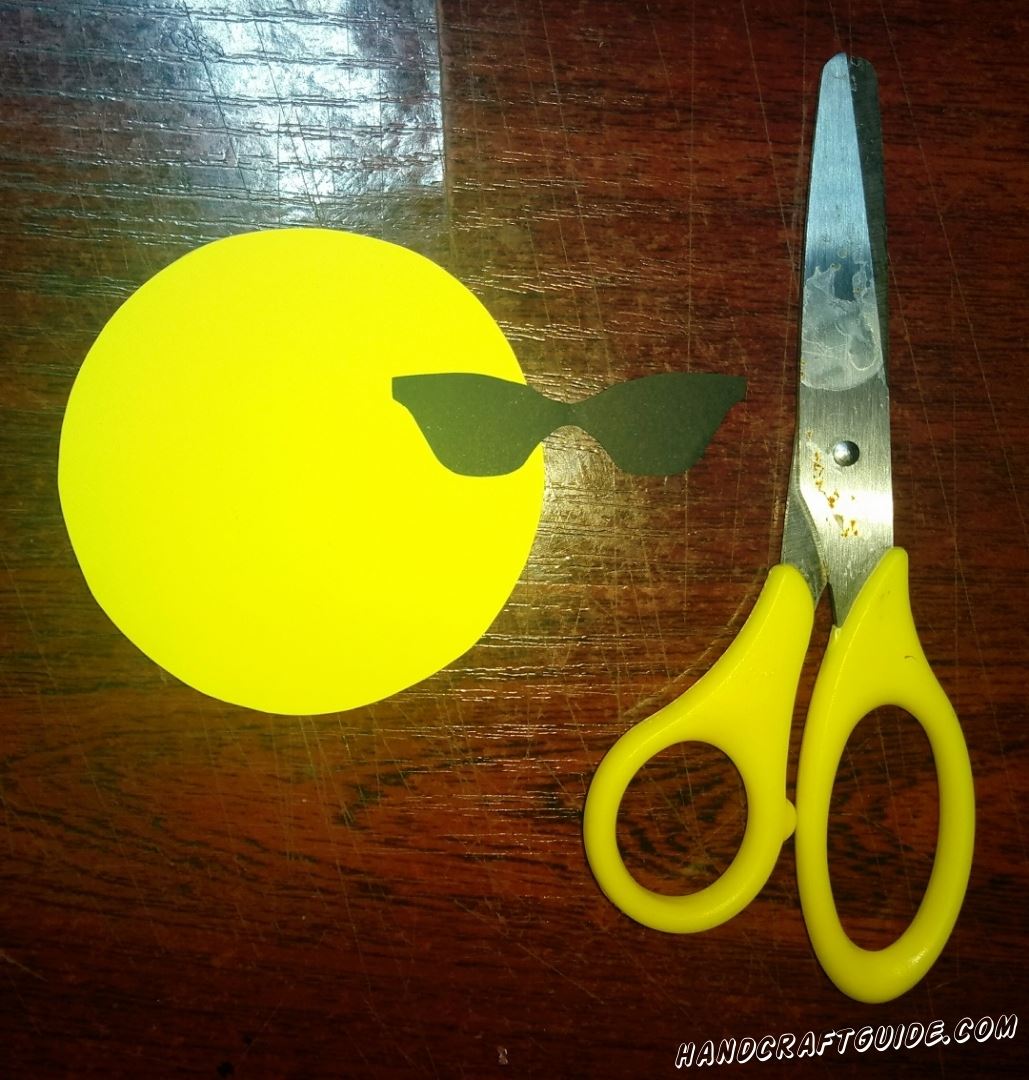 Из бумаги желтого цвета мы вырезаем кружочек. Также вырезаем крутые очки из бумаги чёрного цвета