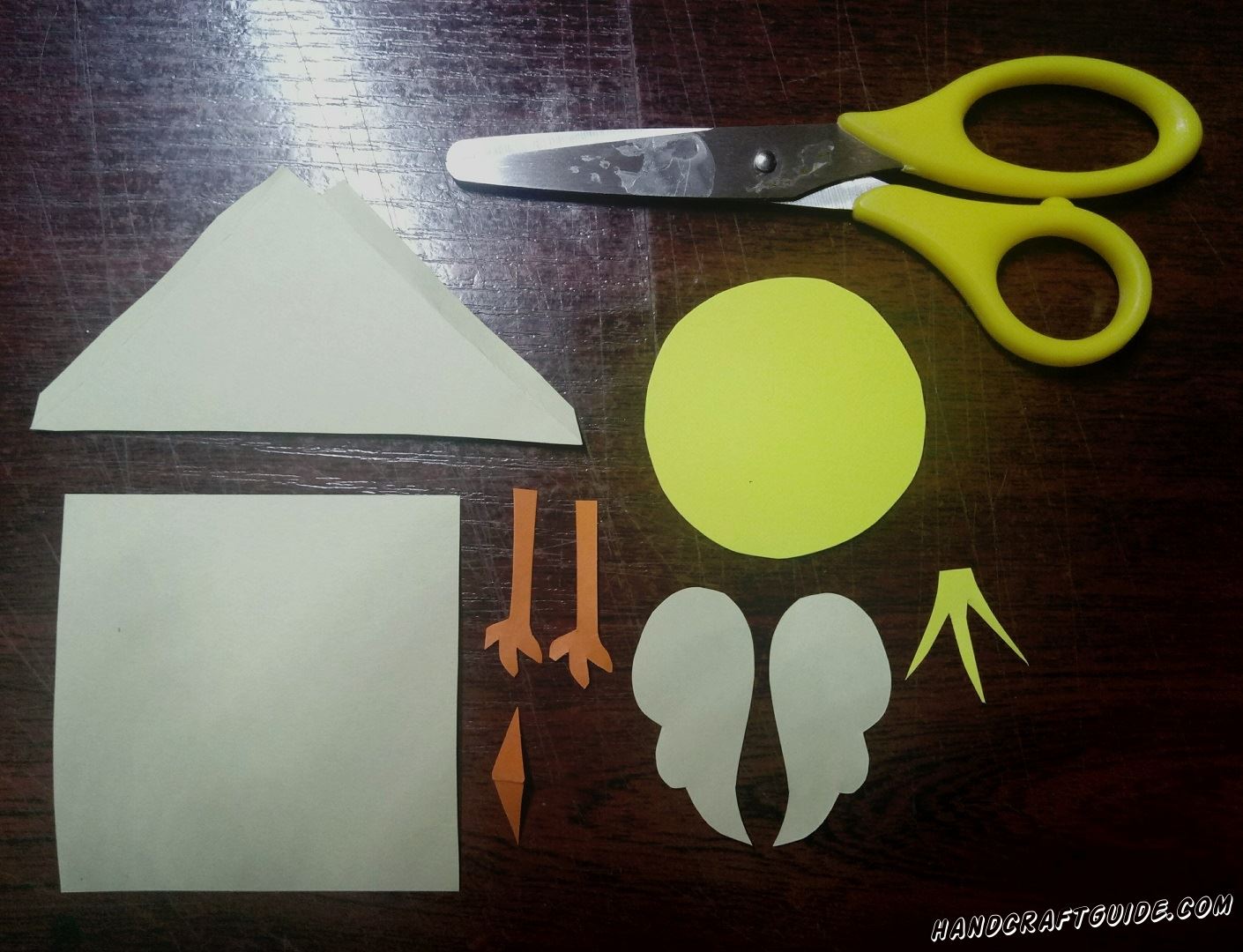 Из белой бумаги мы вырезаем треугольник, квадрат, два маленьких кружка и два крылышка. Теперь берём желтую бумагу и ножницами вырезаем круг и причёску. Осталось только вырезать клювик и две лапки оранжевого цвета